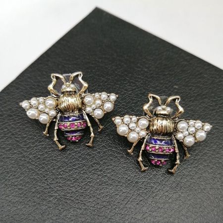 2つの蜂のブローチの詳細なビューで、パールがあしらわれた翼の質感と宝石のアクセントの輝きに焦点を当てています。