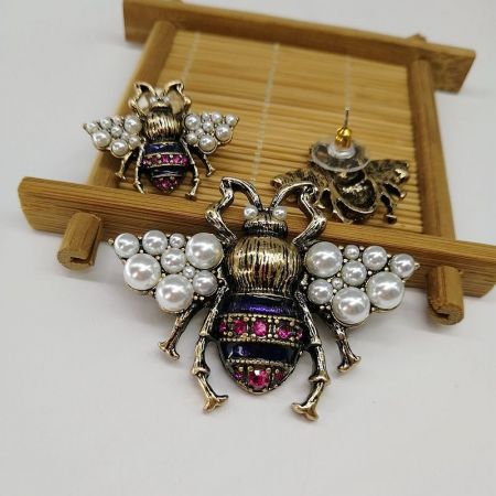 蜂のブローチがマッチングのイヤリングと一緒に展示されており、完全でエレガントなジュエリーセットを示しています。