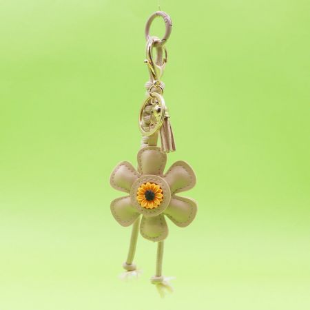 Beige sunflower keychain featuring a tassel and a woven leather strap.