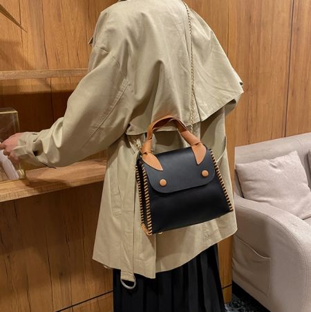 構造と茶色のレザーディテールを示す黒のPUレザーハンドバッグの側面。