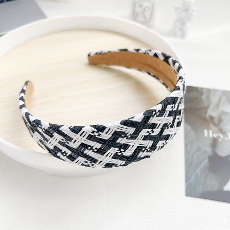 Primer plano de una diadema de rafia tejida a mano con un patrón en blanco y negro.