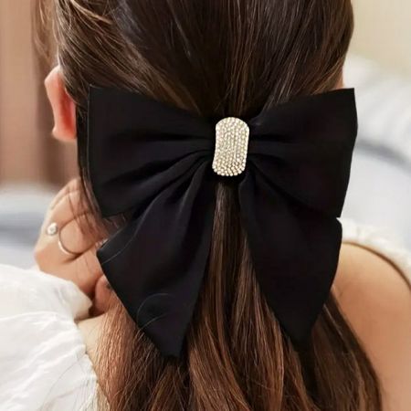 Una modelo mostrando el clip para el cabello con lazo negro, sosteniendo elegantemente su largo cabello castaño.