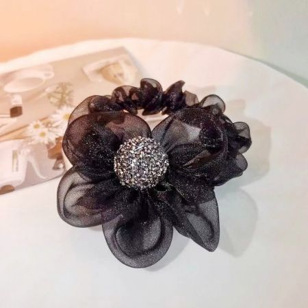 Detailed view of the black fabric flower scrunchie with a glittery center.