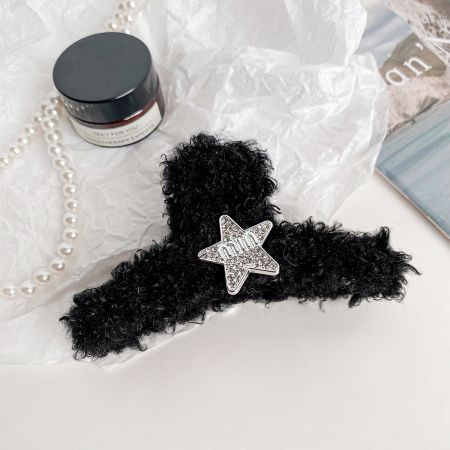Um elegante clipe de cabelo de pelúcia preto decorado com uma estrela prateada.