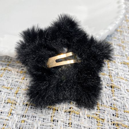 Vue détaillée de la pince à cheveux en peluche étoile noire, mettant en avant le mécanisme de clip en métal doré.