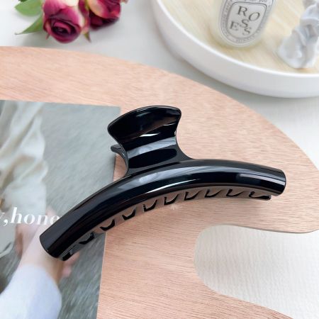 スリークな黒いアーク形状のヘアクロークリップのクローズアップ。