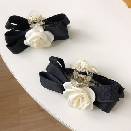 A pair of white camellia flower hair claw clips with black ribbons, shown against a clean background.