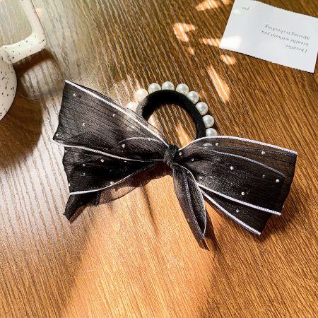 Close-up of a black elastic hair tie with an elegant decorative bow.