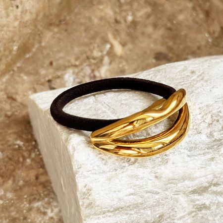Una sola diadema negra con el elegante acento en forma de labios dorados mostrado claramente.