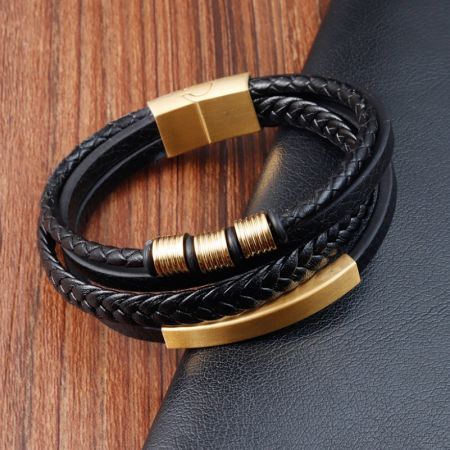 Närbild av det svarta läderarmbandet för män med guldpläterad rostfri stålsplitt.
