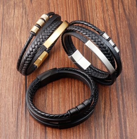 Ett set med tre svarta läderarmband som visar olika metallfinish: guld, silver och svart.