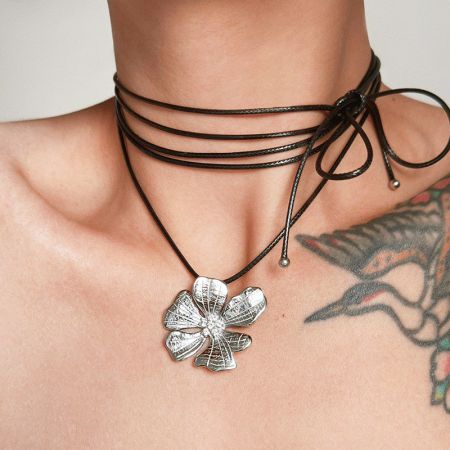 Collana con fiore di ibisco argentato indossata da un modello, che mostra il cordino in pelle.
