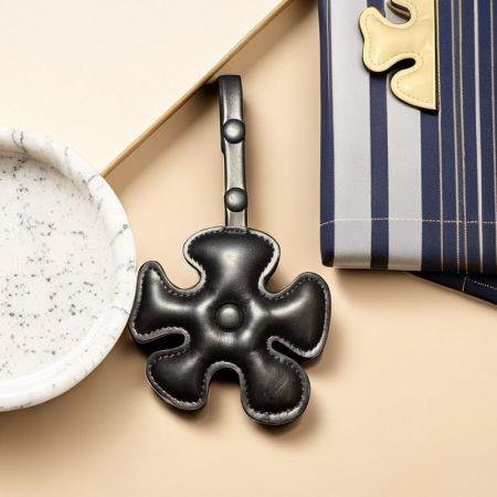 Un elegante llavero de cuero negro con diseño de trébol de cuatro hojas, mostrado en un entorno de producto.