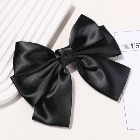 Vista frontale dell'elegante accessorio per capelli a fiocco nero in raso.
