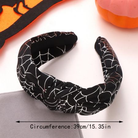 Close-up of a black knotted headband with a white spiderweb pattern for Halloween.