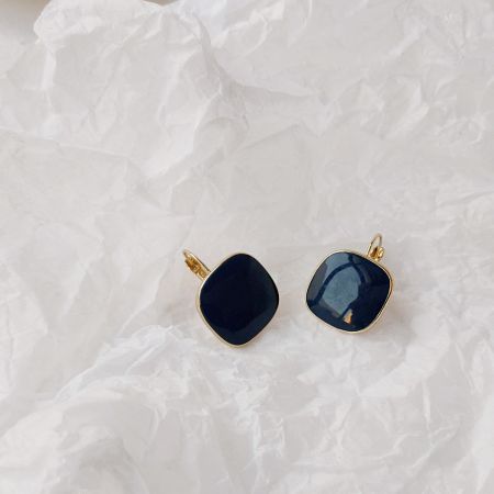 Close-up detail of the black stone and gold setting square earrings.