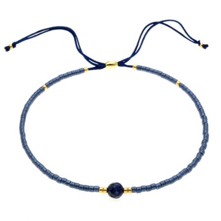 Un delicato braccialetto in perline blu con accenti dorati e chiusura a cordoncino regolabile.