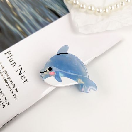 プランナーの上にあるかわいい青いイルカのヘアクリップのクローズアップ。