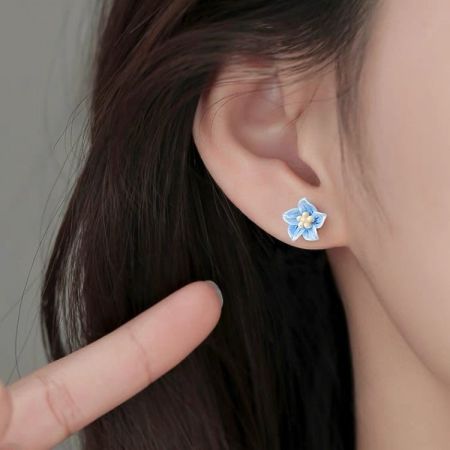 Een model met de elegante S925 blauwe bloemenstud oorbel om de grootte en stijl te tonen.