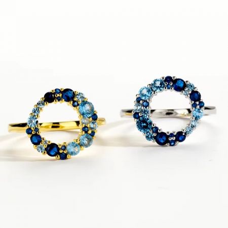 Ein Paar moderne minimalistische Ringe in Silber- und Goldausführungen, jeweils mit einem blauen Edelstein.