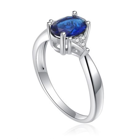 Sido vy av Oval Safir och Zirkonia Ring, som visar den framträdande blå ädelstenen och rhodiumbelagd band.