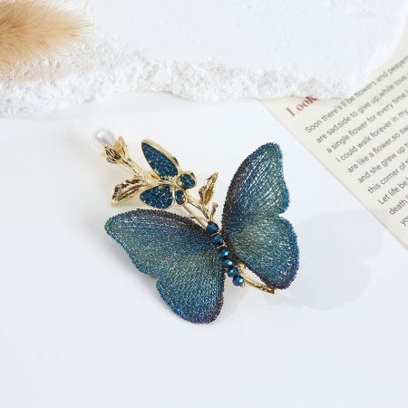 Vista detalhada do broche de borboleta bordado azul sereno com elegantes acentos em ouro.