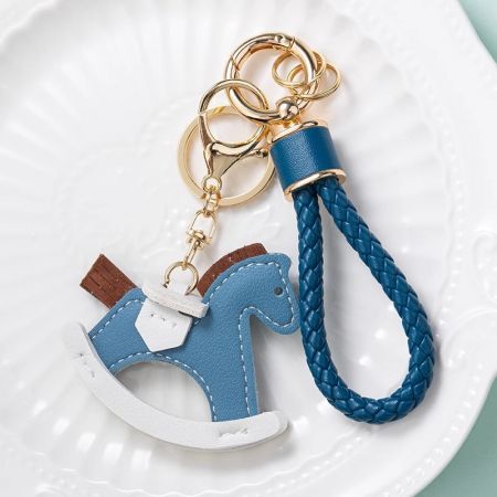 編み込みストラップと金のクラスプが付いた鮮やかな青のレザーのポニーキーチェーン。