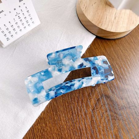 Dos elegantes clips de pelo de acetato veteado en azul y blanco exhibidos juntos.
