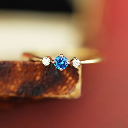 Gedetailleerde productfoto van de geboortesteenring van september, met de levendige blauwe centrale steen.