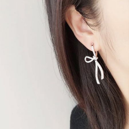 Modello che indossa i dolci orecchini a forma di fiocco in argento CZ per mostrare il loro aspetto elegante.