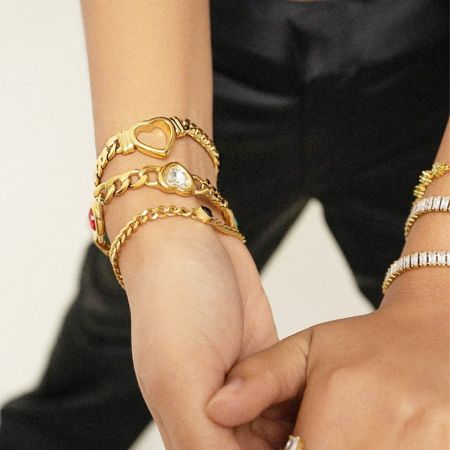 En samling av kraftiga guldtonade armband, inklusive hjärtdesignen.