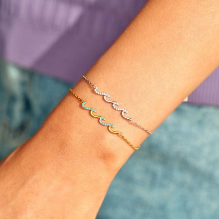 Una colección de pulseras elegantes que incluye el diseño Glittering Waves en el brazo de un modelo.