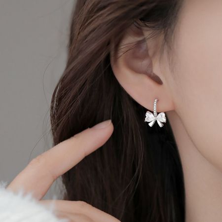 모델의 귀에 반짝이는 큐빅 지르코니아 리본 귀걸이를 클로즈업한 모습.