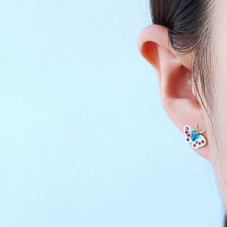 小さくてカラフルな蝶のスタッドイヤリングを着用したモデル。