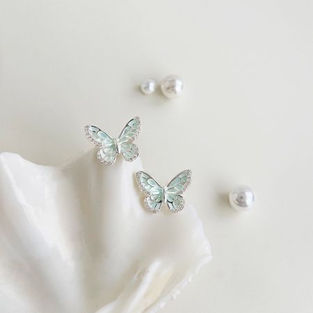 Boucles d'oreilles en papillon plaquées argent en gros avec émail vert menthe (5 paires) - Une paire de boucles d'oreilles en papillon plaquées argent en gros avec émail vert menthe et strass clairs, élégamment présentée sur une coquille blanche.