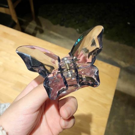 Scatto dettagliato di una clip per capelli a forma di farfalla trasparente viola.