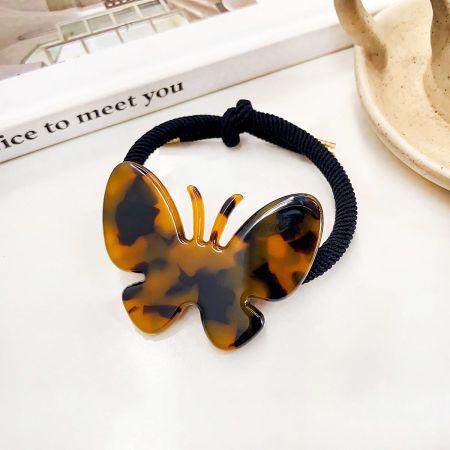 A classic tortoiseshell patterned butterfly hair tie on a black elastic band.
