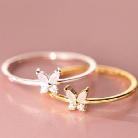 Anelli a farfalla in argento sterling 925 per donne - Set di 5 - Un primo piano di due anelli a forma di farfalla in argento sterling 925 di un set di cinque, uno con finitura in argento lucido e l'altro con finitura in oro radioso, entrambi adornati con gemme trasparenti scintillanti.