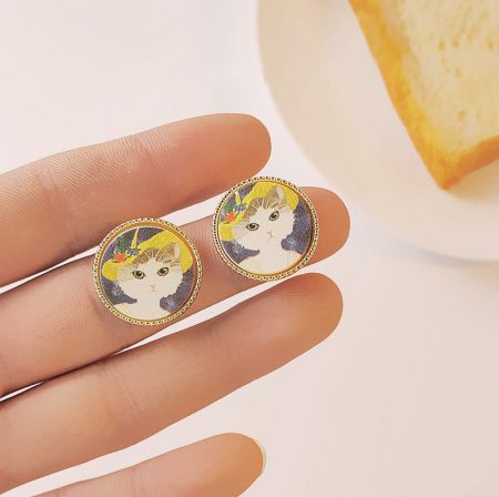 ラウンド14kゴールドフレーム猫の絵画スタッドピアス（5ペア） - ラウンド14kゴールドフレーム猫の絵画スタッドピアスの詳細なスタジオショットで、花の帽子をかぶった複雑な猫のデザインを強調しています。