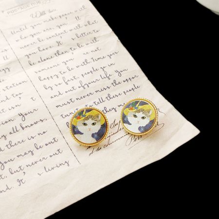 手書きの手紙に添えられた猫の絵画のスタッドピアスが、個人的なタッチを加えています。