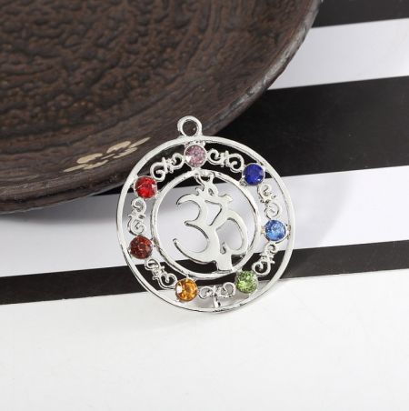 Ein runder silberner Chakra-Anhänger mit dem Om-Symbol, umgeben von sieben bunten Edelsteinen.
