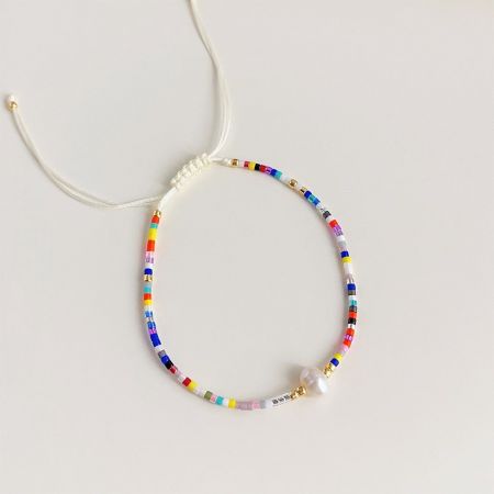 Primo piano di un braccialetto bohemien multicolore con perle centrali.