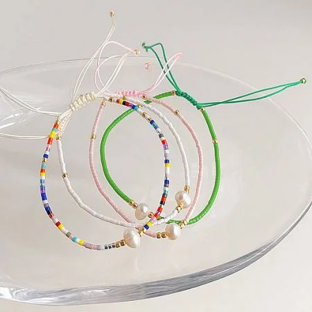 مجموعة أساور الأزياء - مجموعة متنوعة من الأساور الملونة المصنوعة من الخرز واللؤلؤ من JR Fashion Accessories، معروضة بأناقة على طبق زجاجي شفاف.