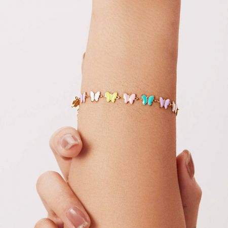 Roestvrijstalen Emaille Vlinderbedels Kettingarmbanden (Set van 5) - Een model dat de roestvrijstalen emaille vlinderbedelarmband draagt, die het delicate en kleurrijke ontwerp op de pols toont.