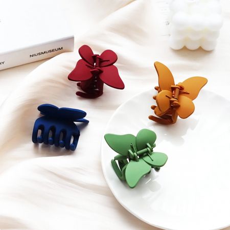 ピンク、青、緑、黄色のパステルカラーの蝶のヘアクリップ4つ。