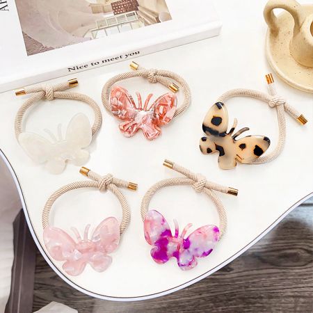 A set of five butterfly hair ties in different colors including pink, blue, and tortoiseshell.