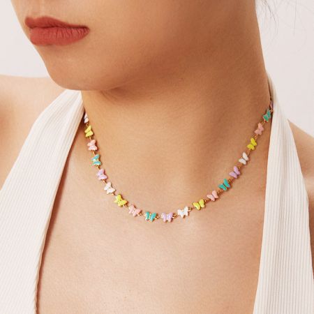 Model showcasing the colorful butterfly necklace with a gentle smile.