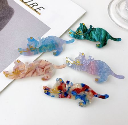 A vibrant collection of five cat-shaped hair clips with unique marbled designs and gold accents.