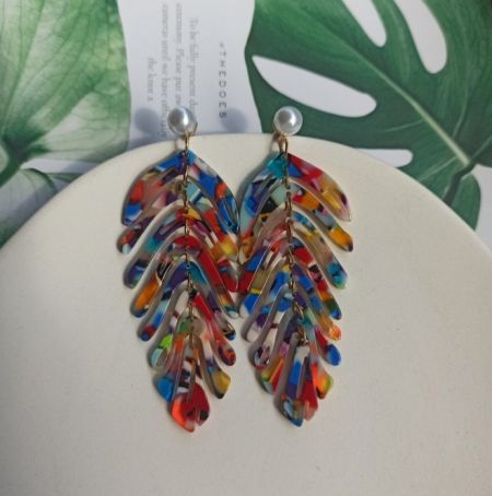 Una variación de los pendientes acrílicos en forma de hoja con un vibrante patrón de plumas multicolores y un arete de perla.