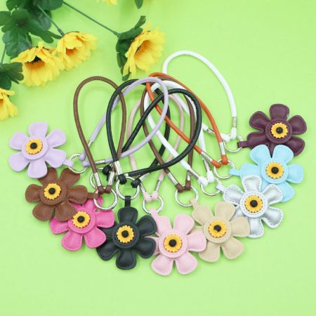 Porte-clés en cuir PU en forme de tournesol avec charme de sac en pompon (vente en gros) - Une collection colorée de porte-clés en cuir PU en forme de tournesol avec des pompons, disponibles en plusieurs couleurs pour la vente en gros.